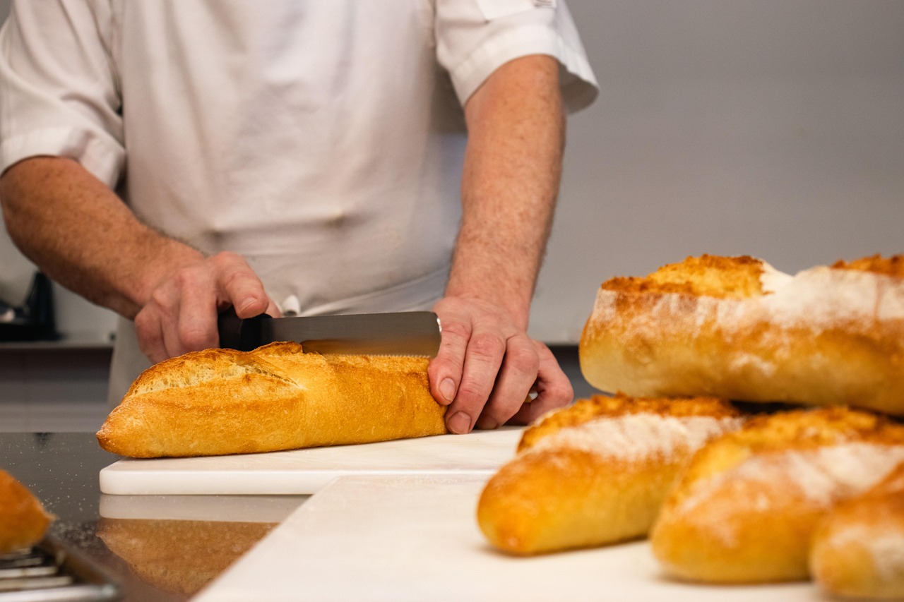 Fresh rolls being sliced by hand on a prep counter