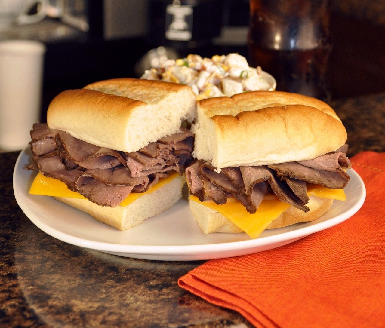 Professional roast beef sandwich served at a restaurant dining table with fresh ingredients